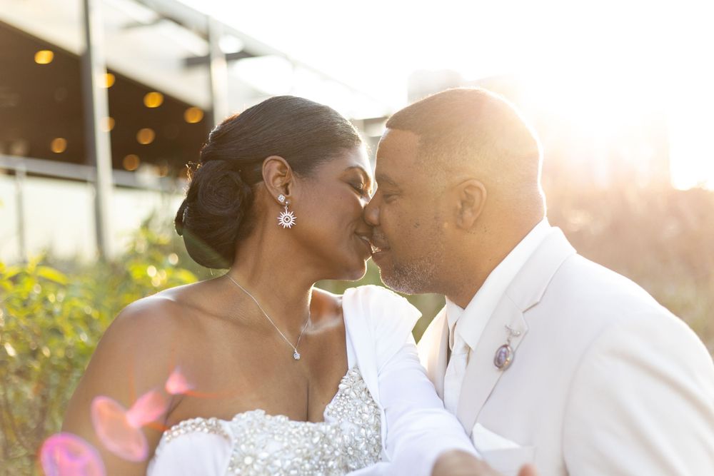 A romantic wedding couple shares a tender moment at sunset with lens flares and natural lighting.