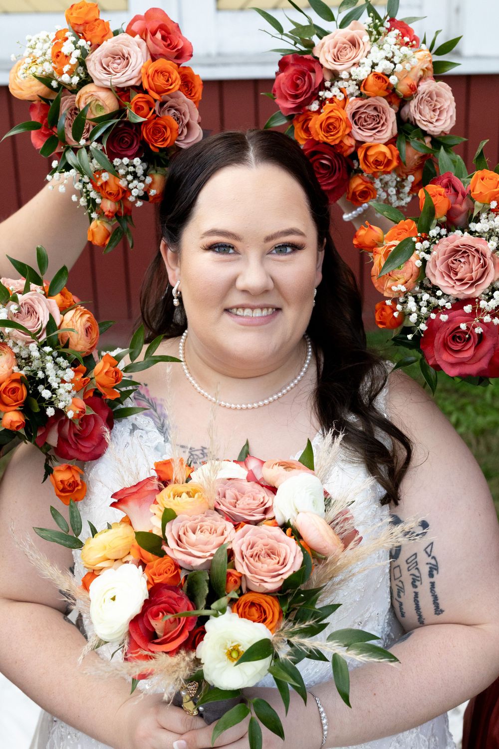 Beautiful floral arrangement with orange and pink roses frames a bridal portrait.