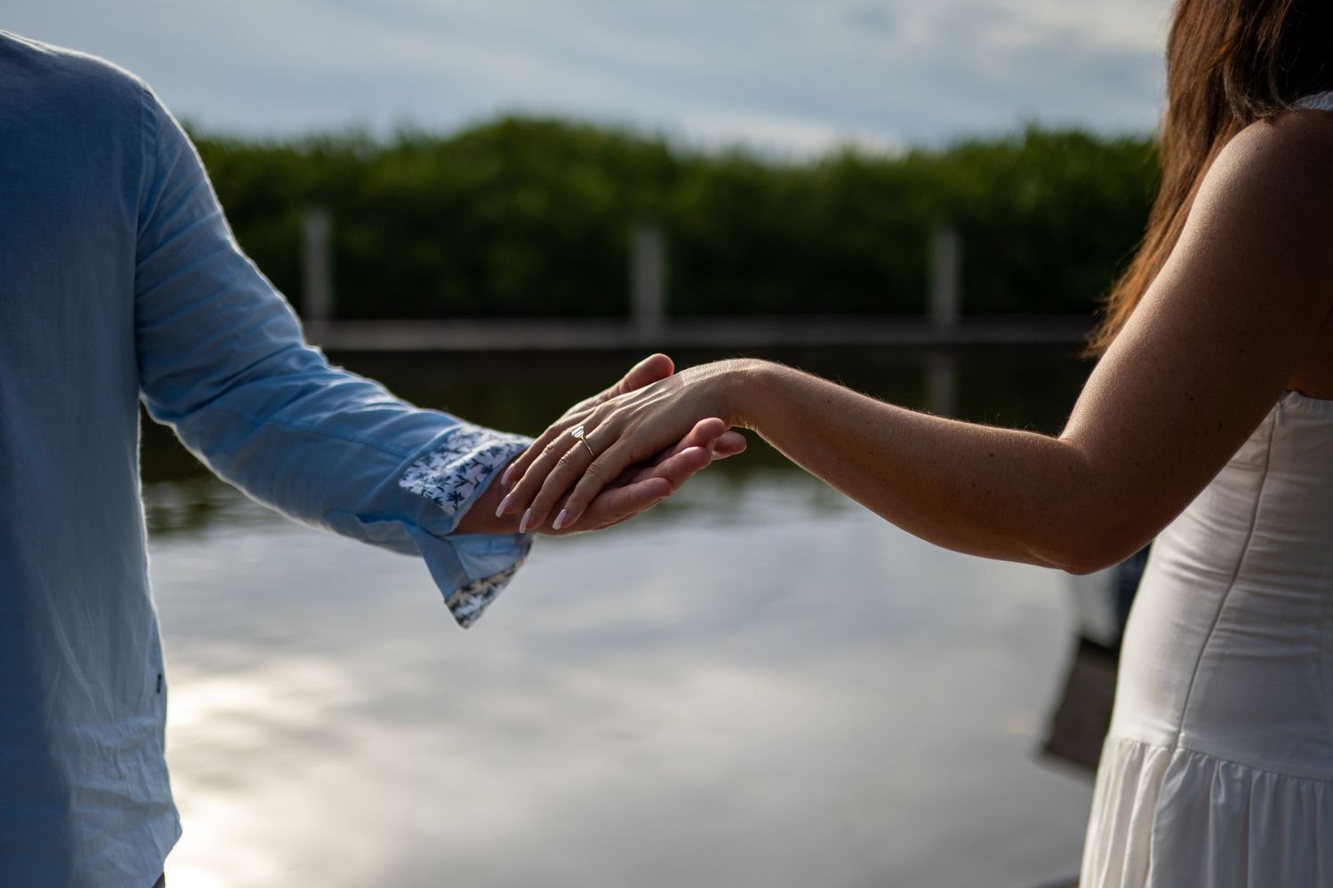 Close-up shots of hands holding champagne glasses during sunset celebration.