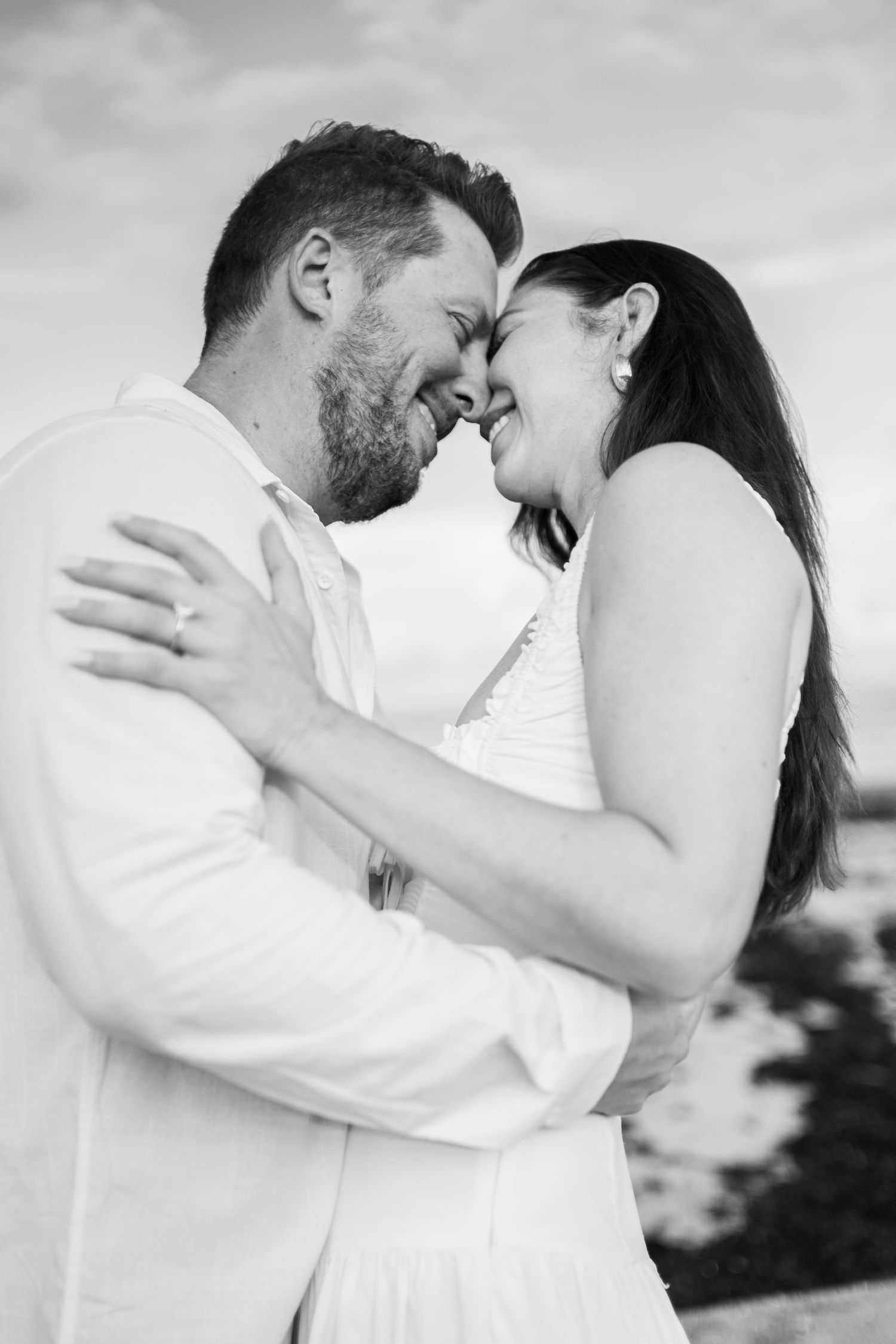 Black and white portrait of a couple sharing an intimate embrace outdoors.