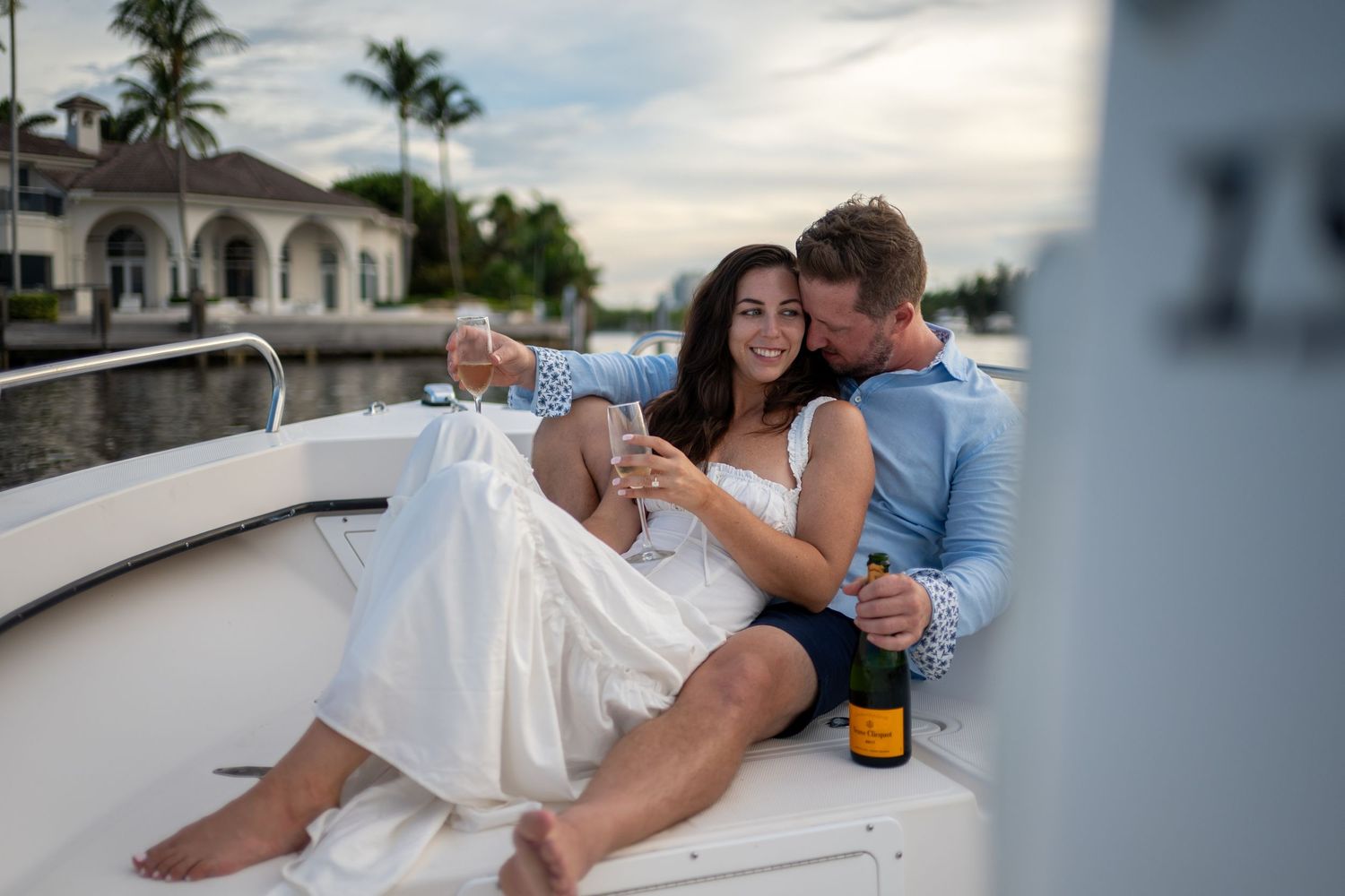 Couple relaxing together on a white boat deck during a romantic sunset photoshoot.