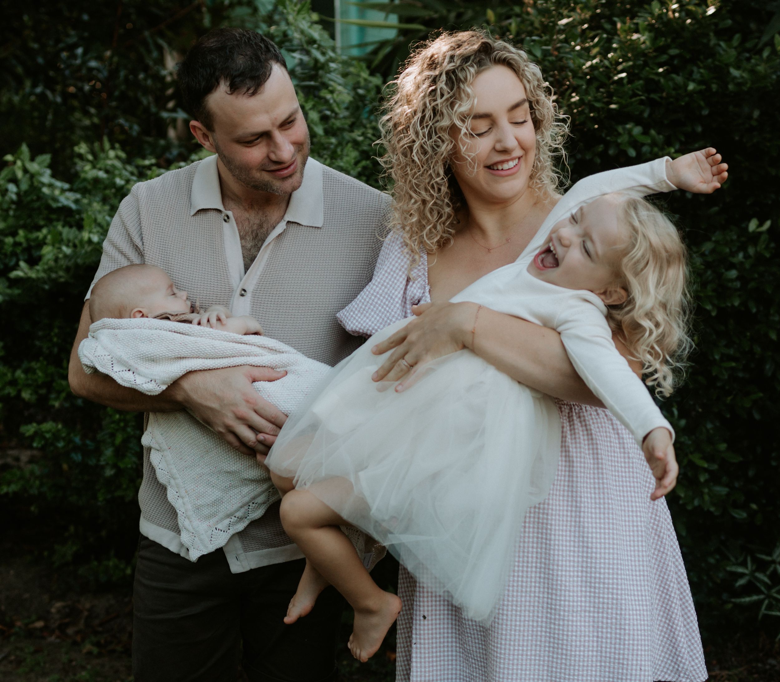 A romantic couple shares tender moments in a garden setting during a lifestyle photoshoot.