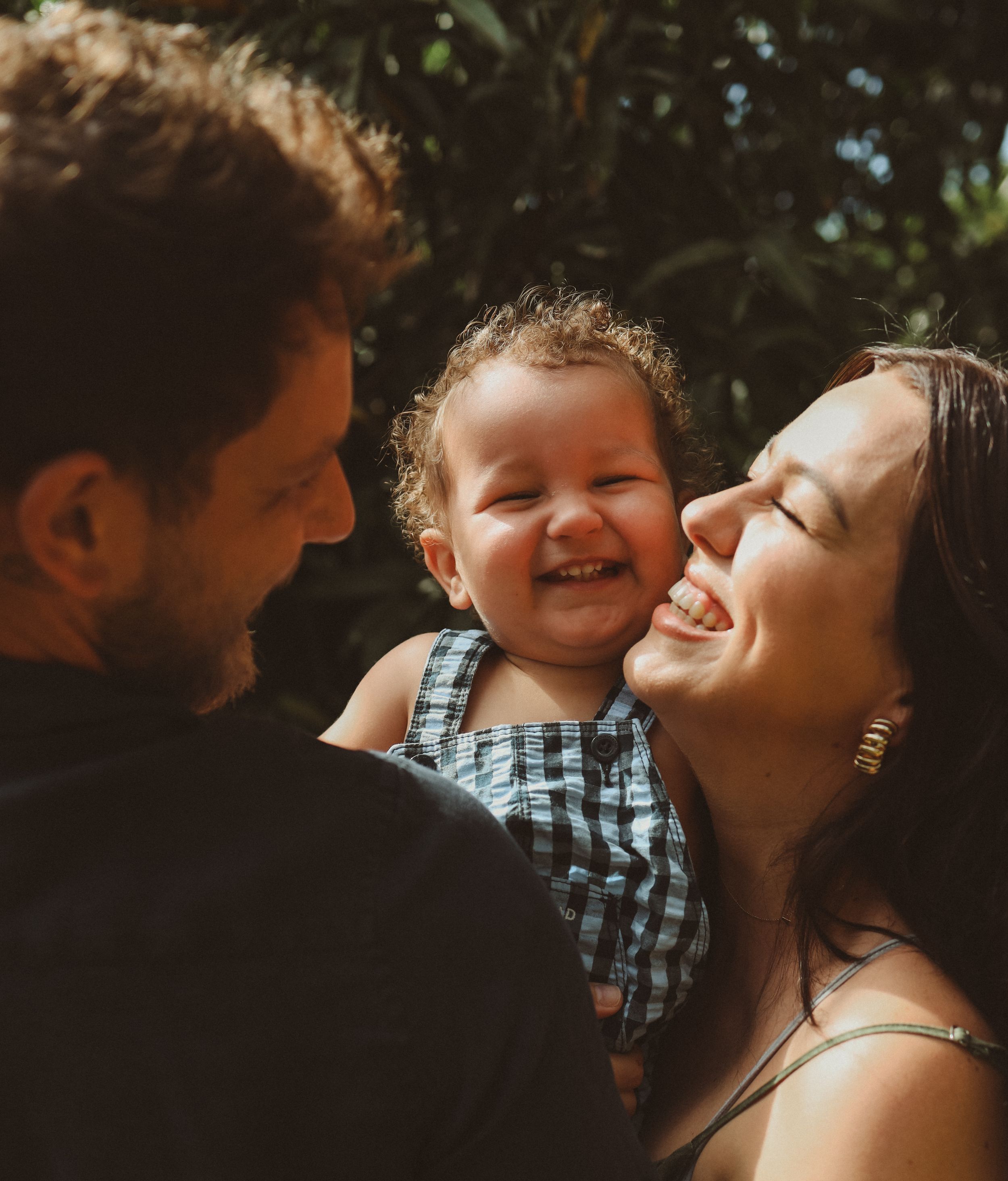 A happy family sharing an intimate candid moment together outdoors on a sunny day.