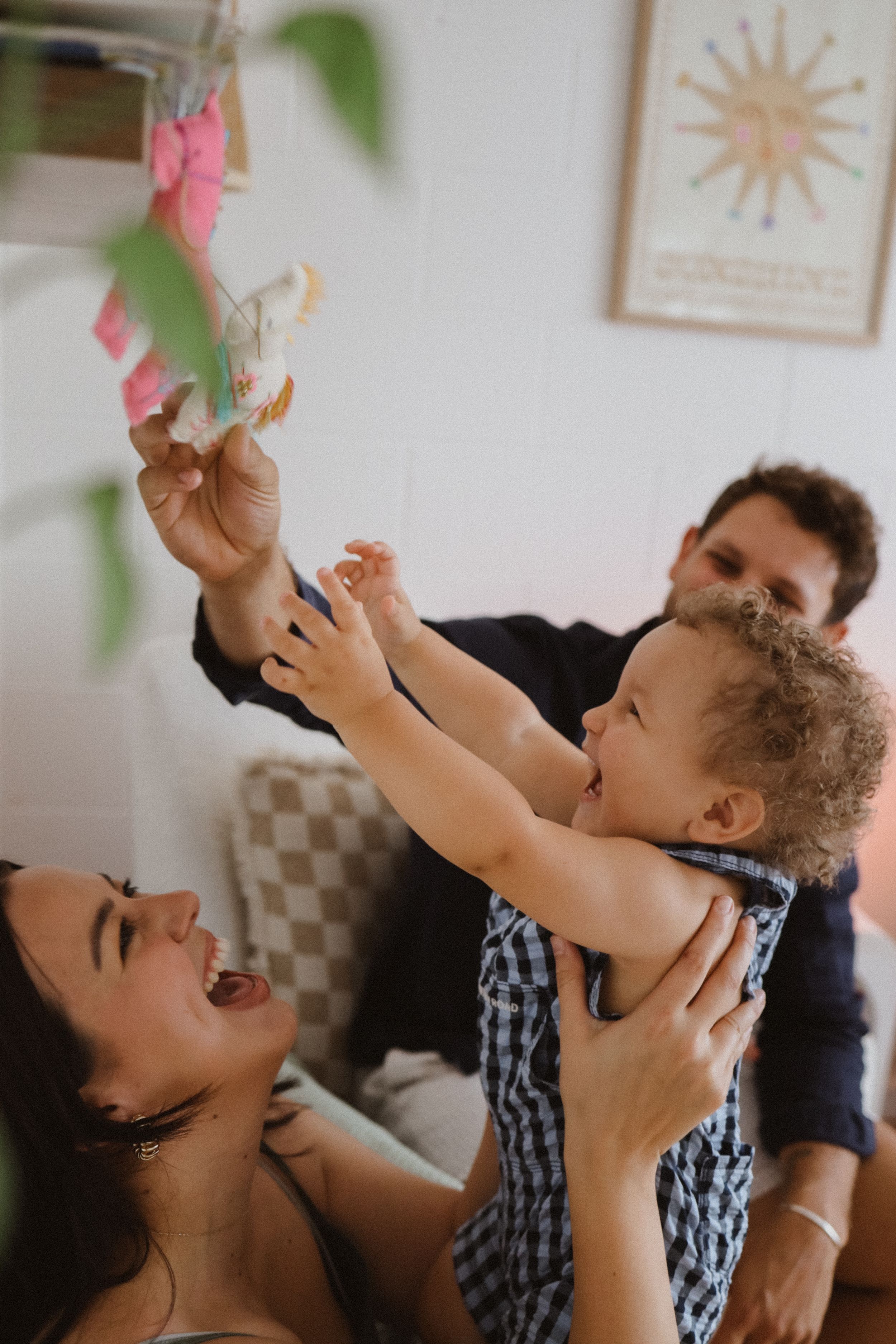 A joyful moment shared between family members playing together on a couch with sunlight streaming in through a window.