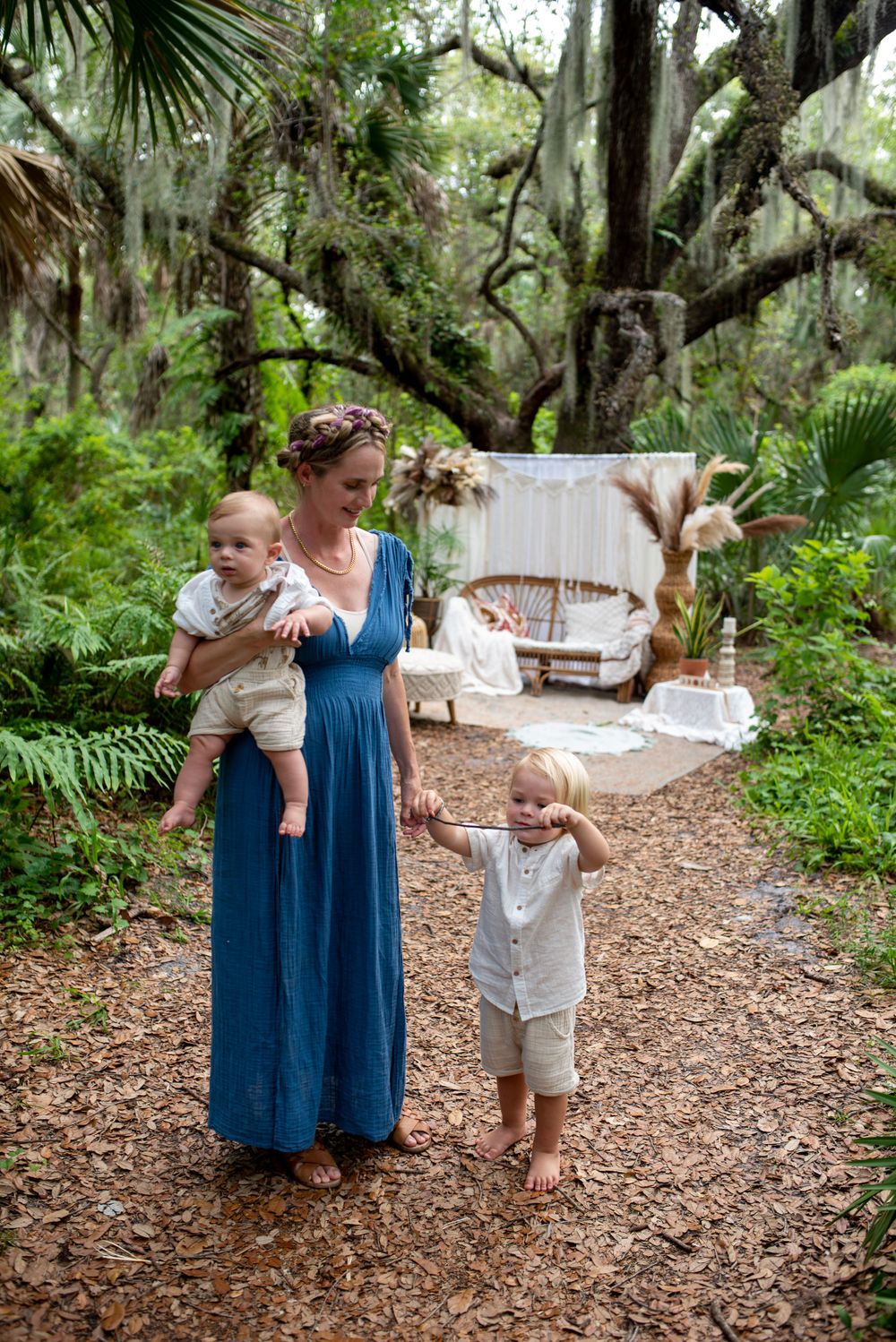 A family walks along a nature trail lined with Spanish moss and palm trees.