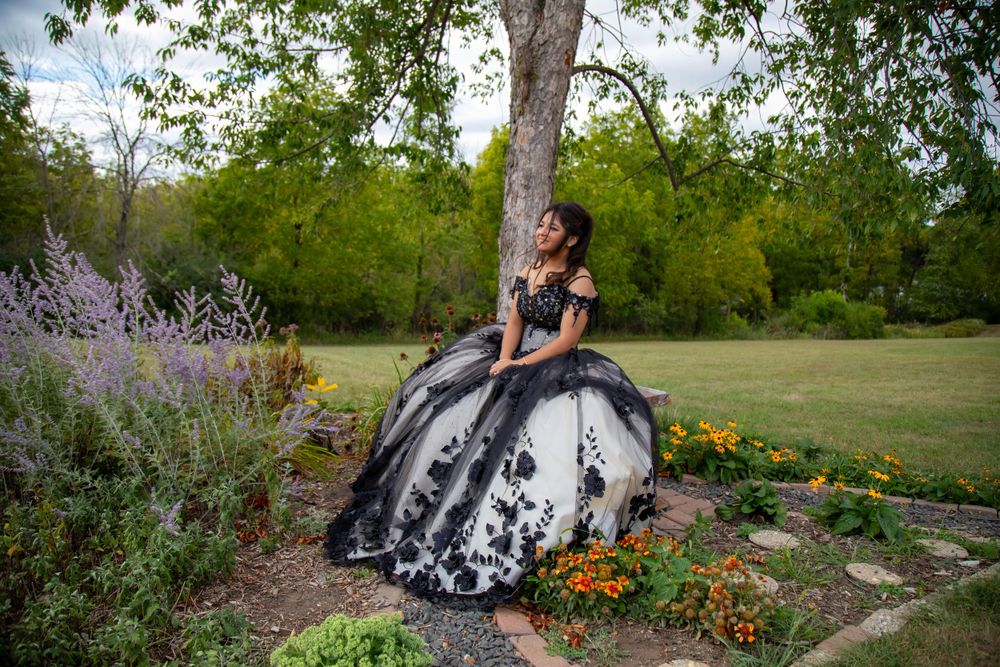 A dramatic black and white ballgown photographed in a garden setting with colorful flowers.