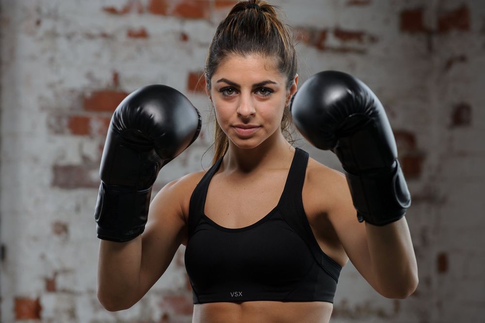 Portrait of a woman fighter with her guard up wearing black boxing gloves and black tank top in Hartford, CT