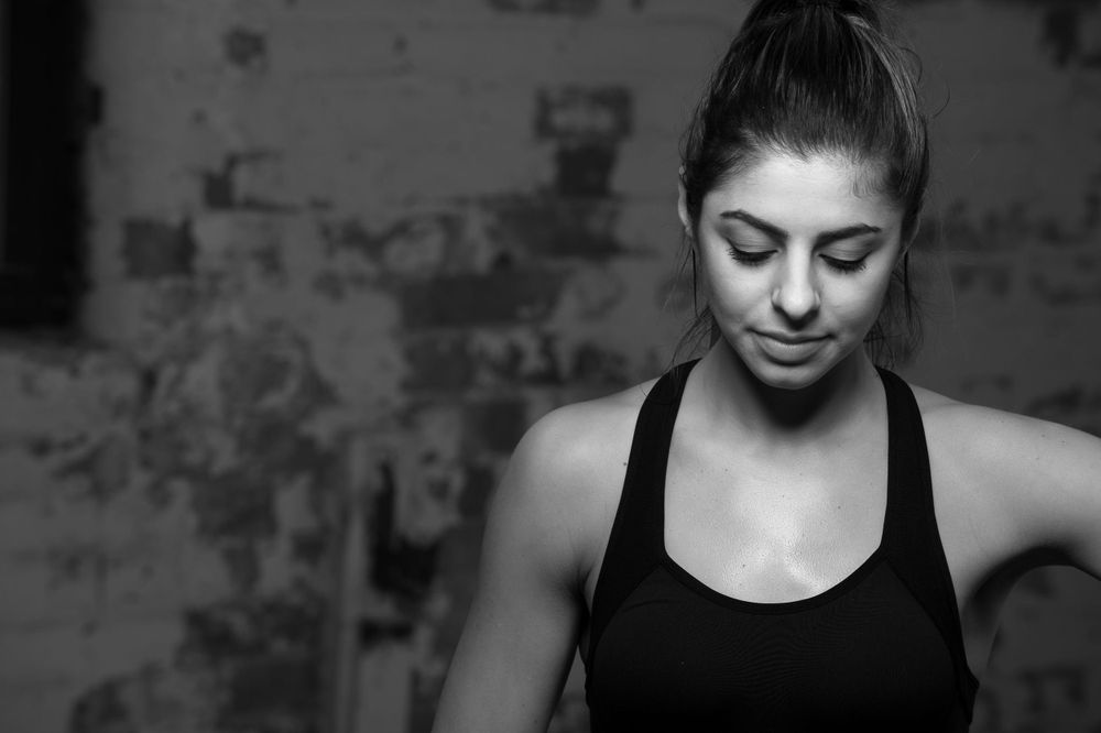 Close up black and white portrait of a sweaty female fighter in a black tank top