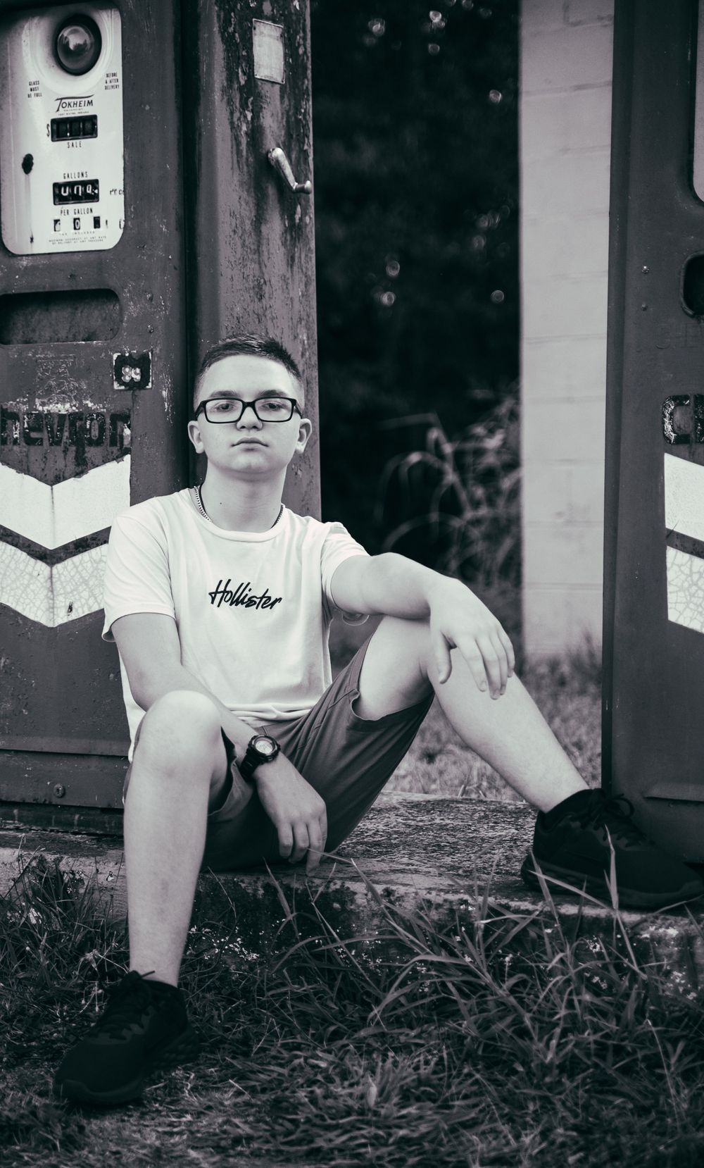 Teen boy with vintage gas pump background in black and white at Rankins Grocery, Anderson, South Carolina.