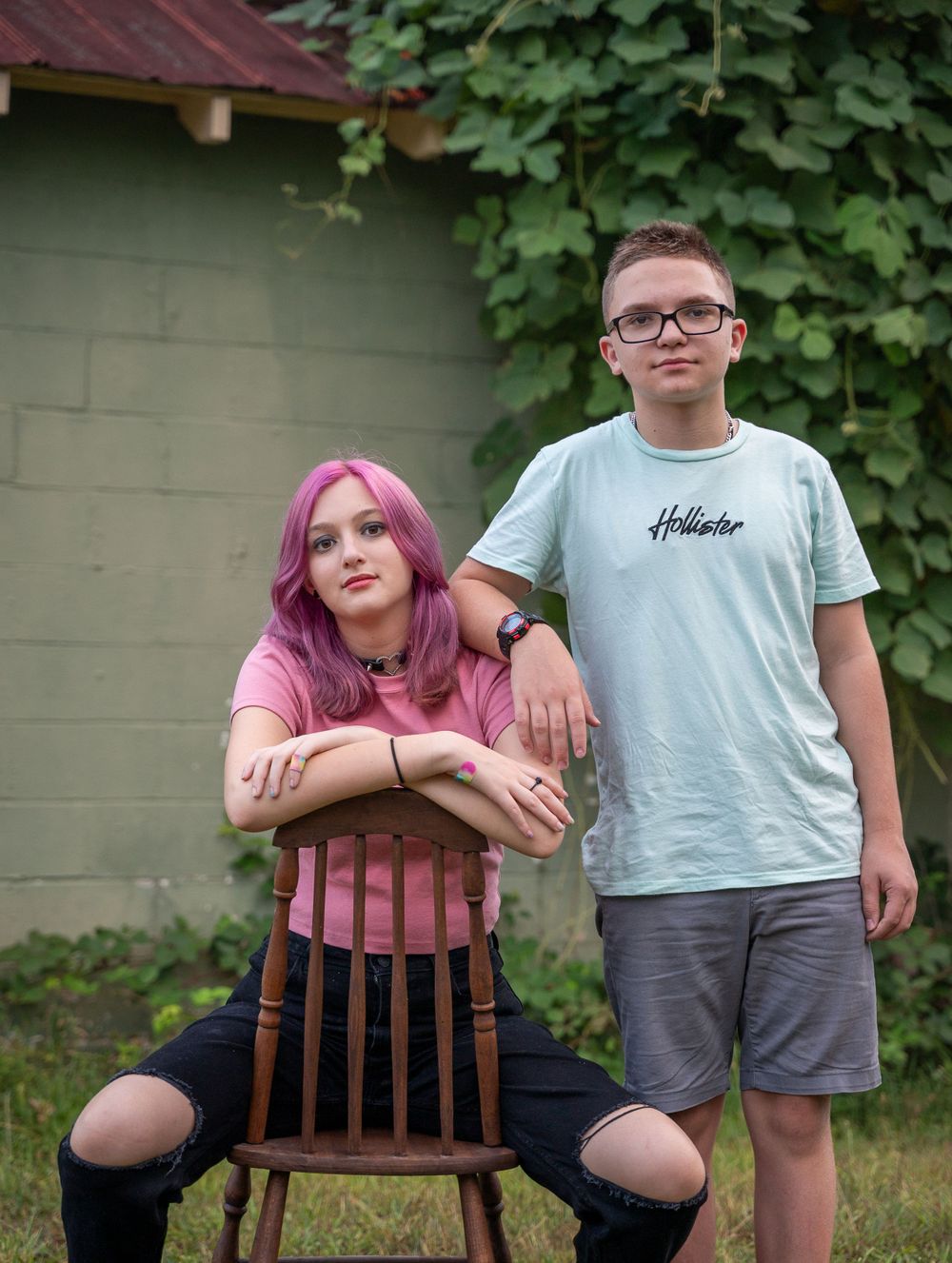 Teen siblings on with chair in front of an old gas and grocery store at Rankins Grocery, Anderson, South Carolina.