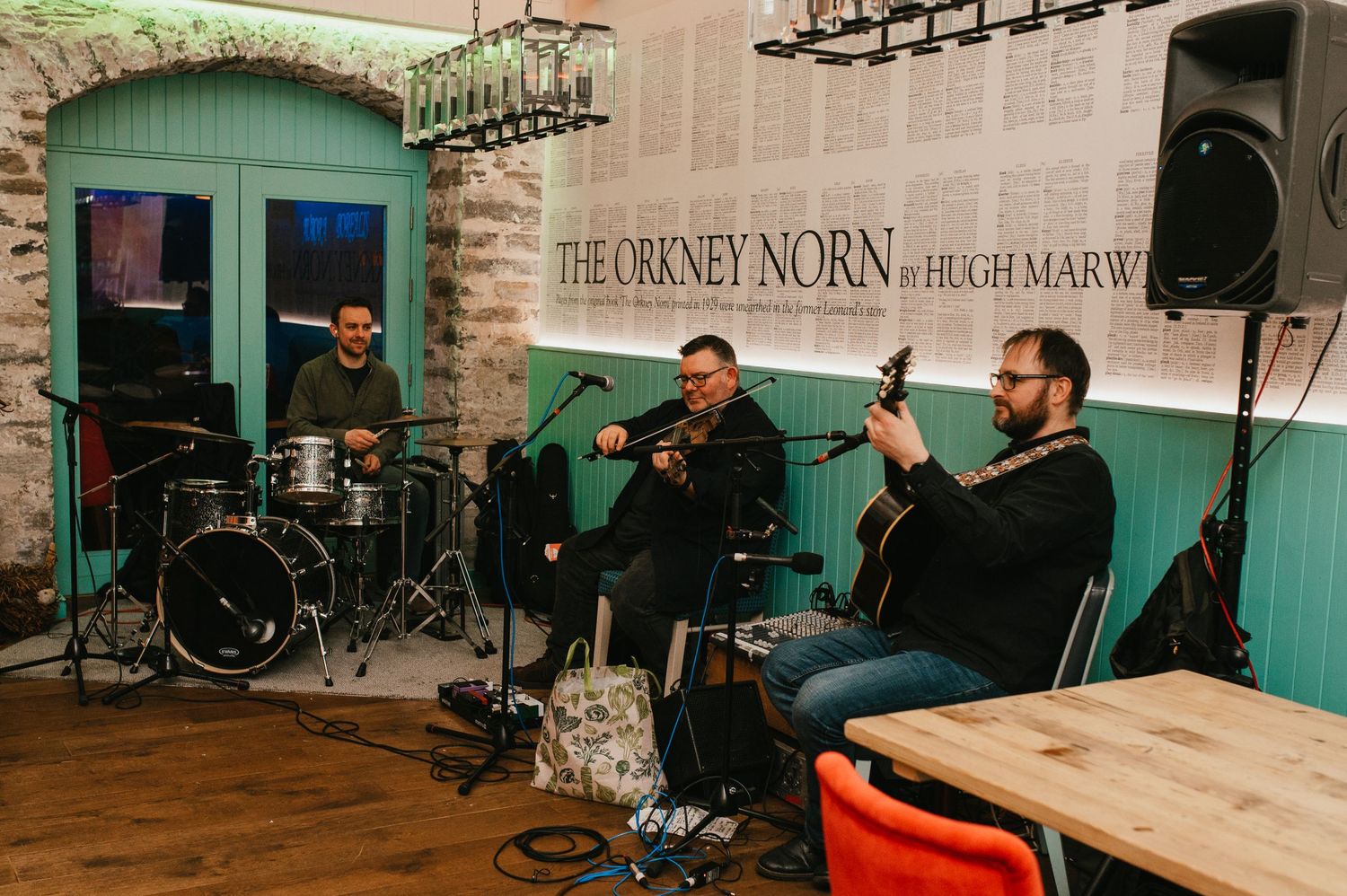 Musicians performing in a rustic venue with green walls and vintage decor.
