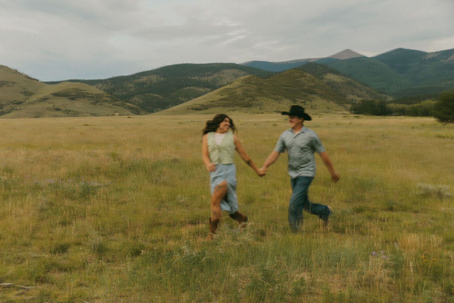People running and jumping through a scenic mountain meadow.