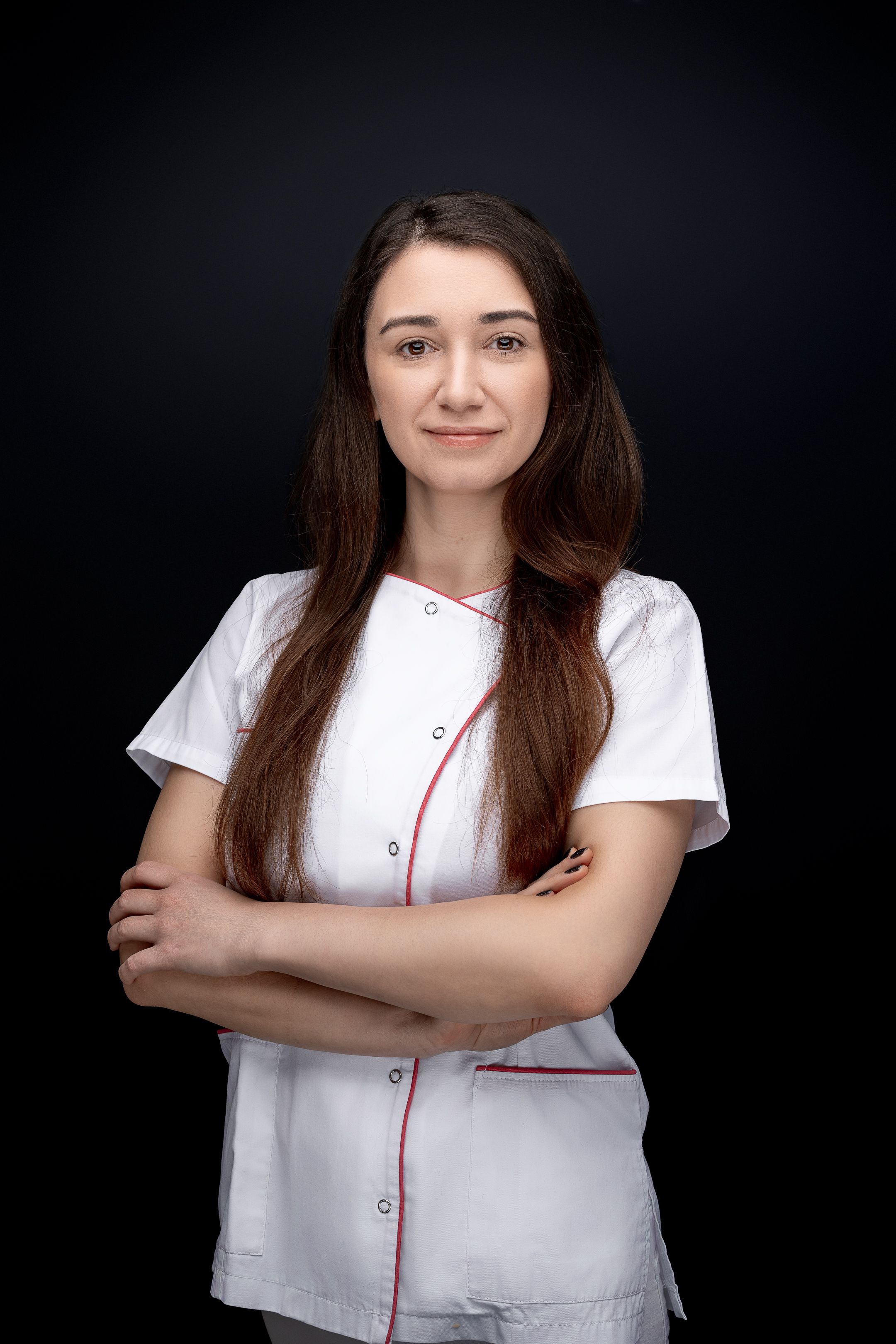 Healthcare professional in white uniform stands confidently against dark background.