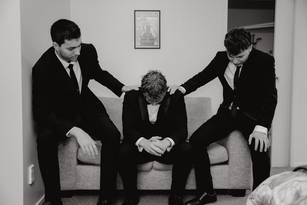 A candid black and white photo of three people sharing an emotional moment on a couch.