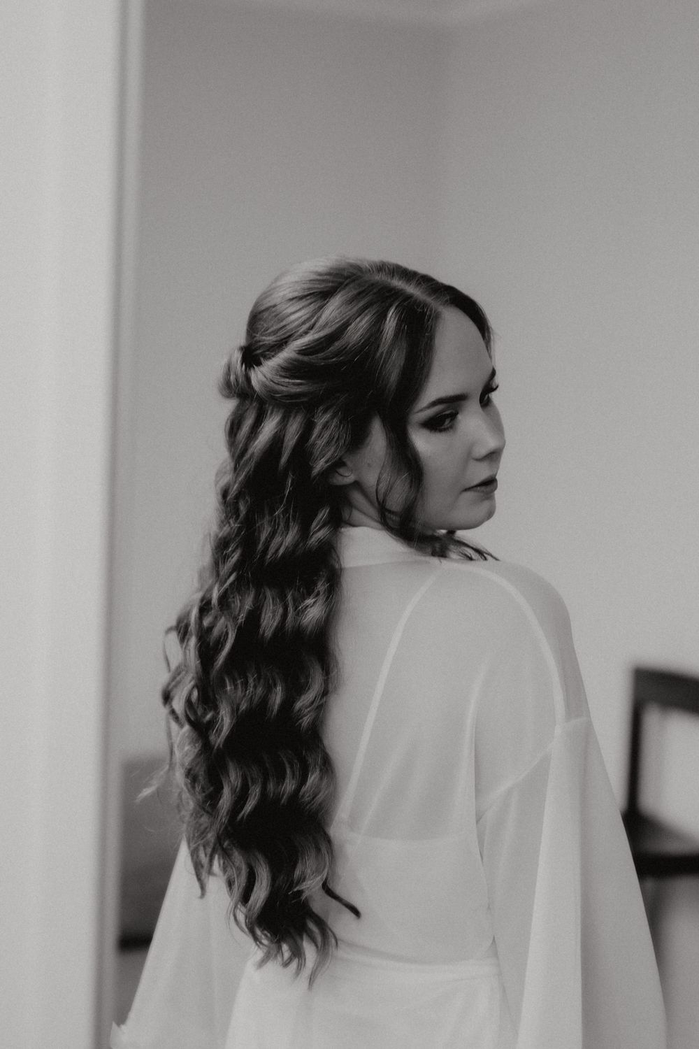 Elegant bridal portrait showing intricate hairstyle with flowing curls and sheer white robe.