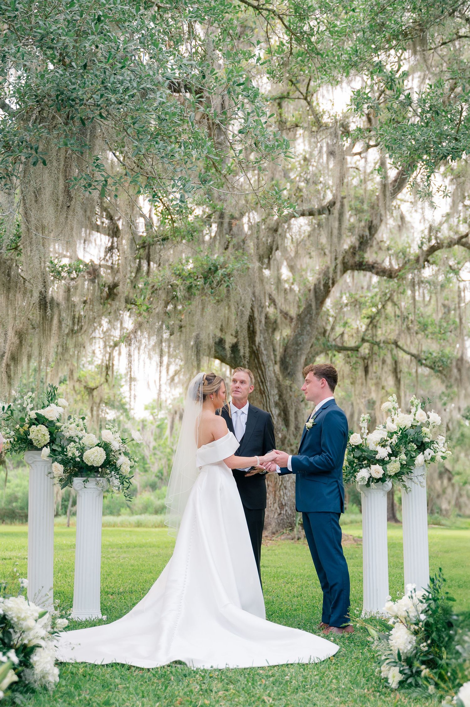 Wedding couple sharing tender moment under oak trees in natural sunlight.