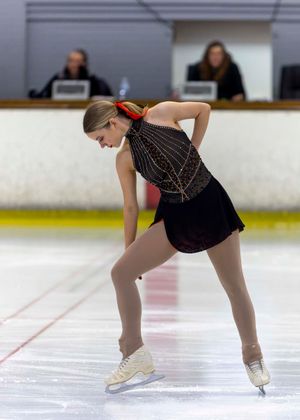 Isabelle McKewen in a black dress gracefully skating on ice. Photo by Nick Wigmore Photography.