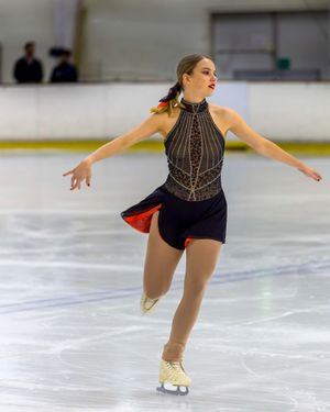 Isabelle McKewen in a black dress gracefully skating on ice. Photo by Nick Wigmore Photography.