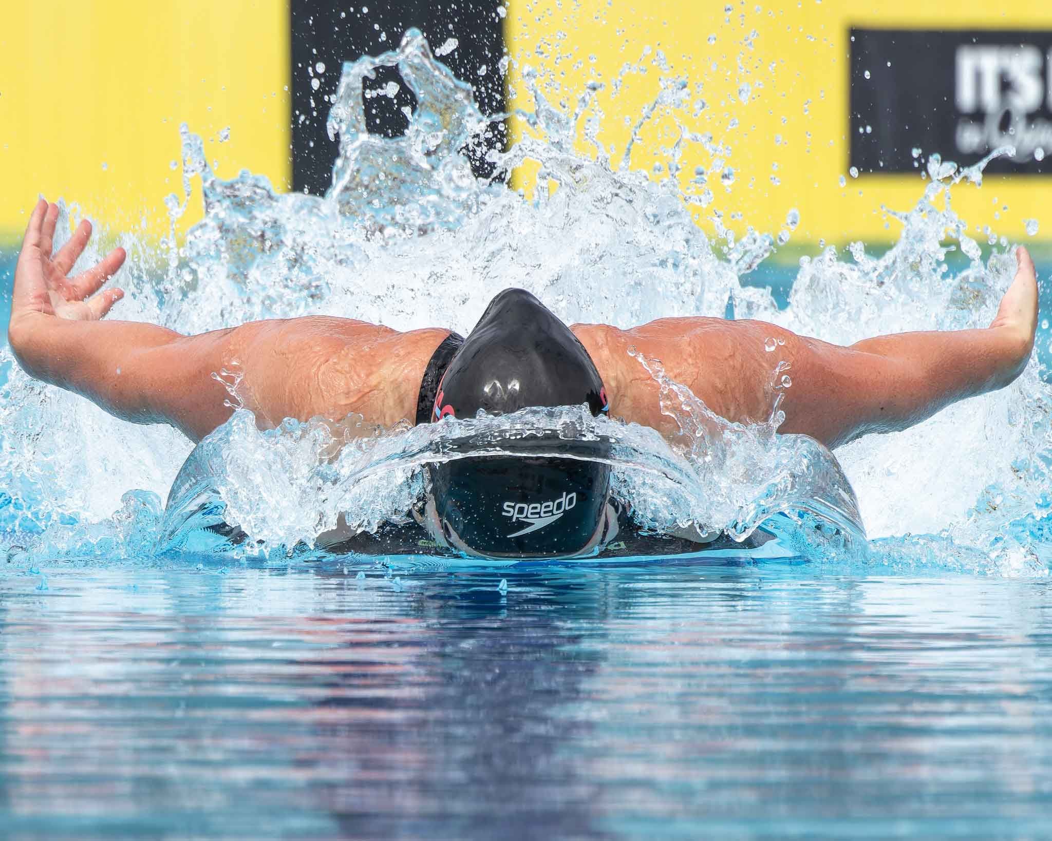 Dynamic shot of butterfly swimmer creating splash during competitive race.