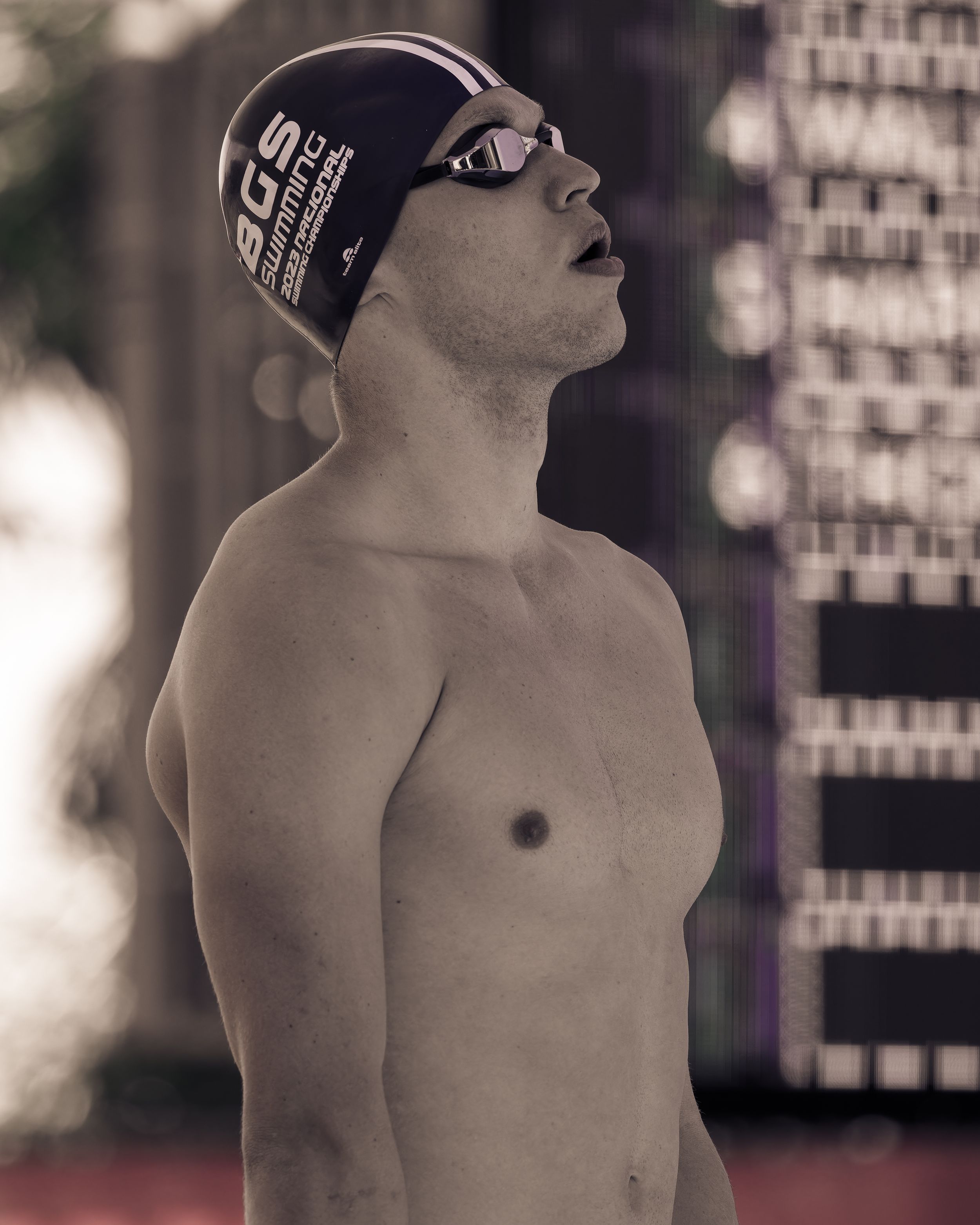 Swimmer in black LCM cap looks upward before competitive race.