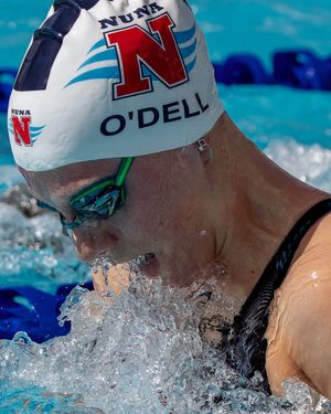 Close-up of swimmer in Nebraska cap performing breaststroke with water splashing.