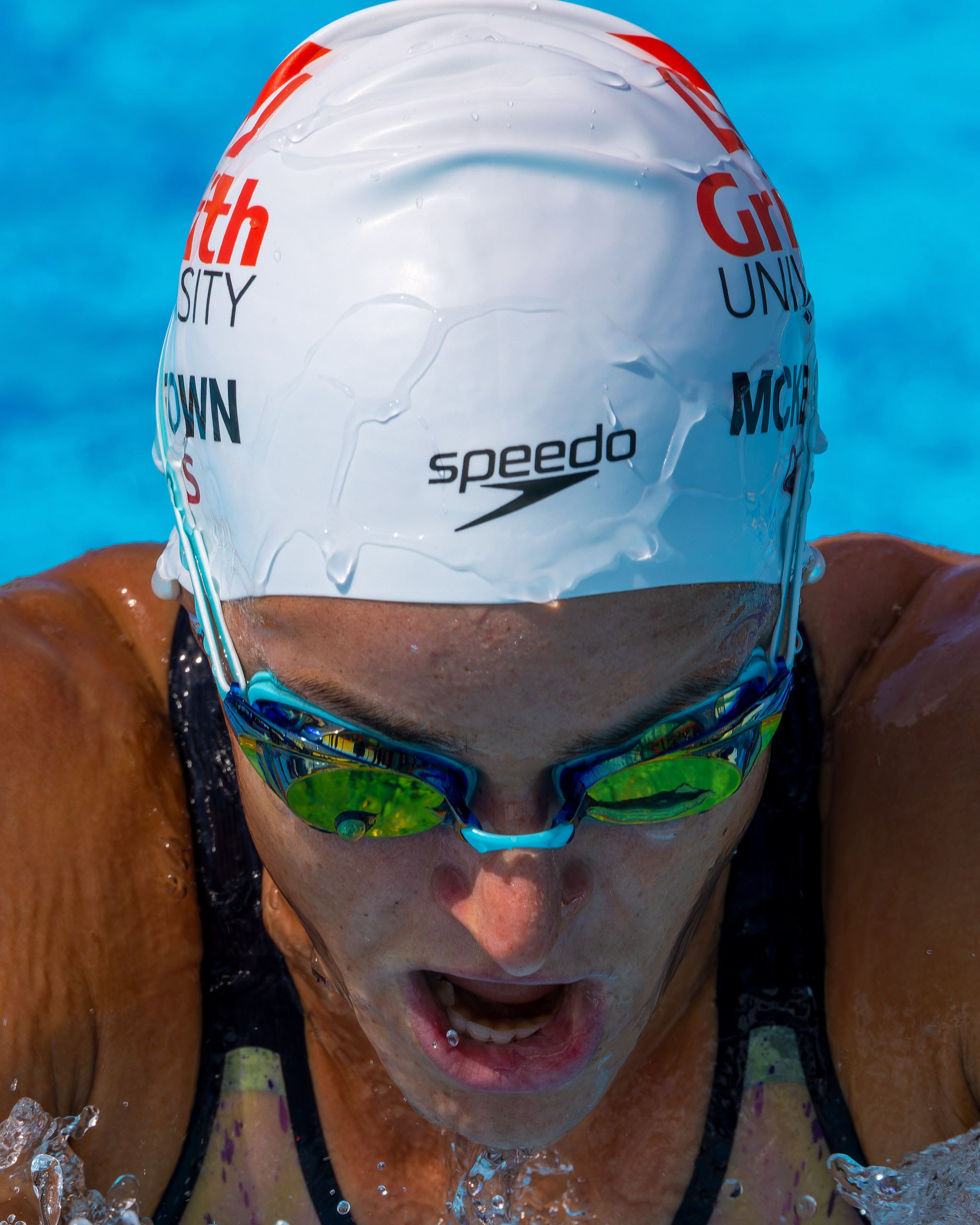 Competitive swimmer wearing Speedo cap and goggles during race in swimming pool.