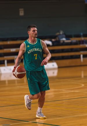 Basketball player in green Australia uniform number 7 dribbling ball during game.