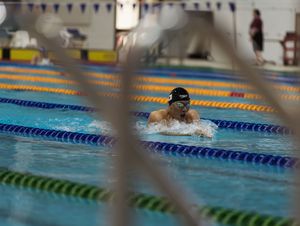 Swimmer performing breaststroke in competitive pool with lane lines visible.