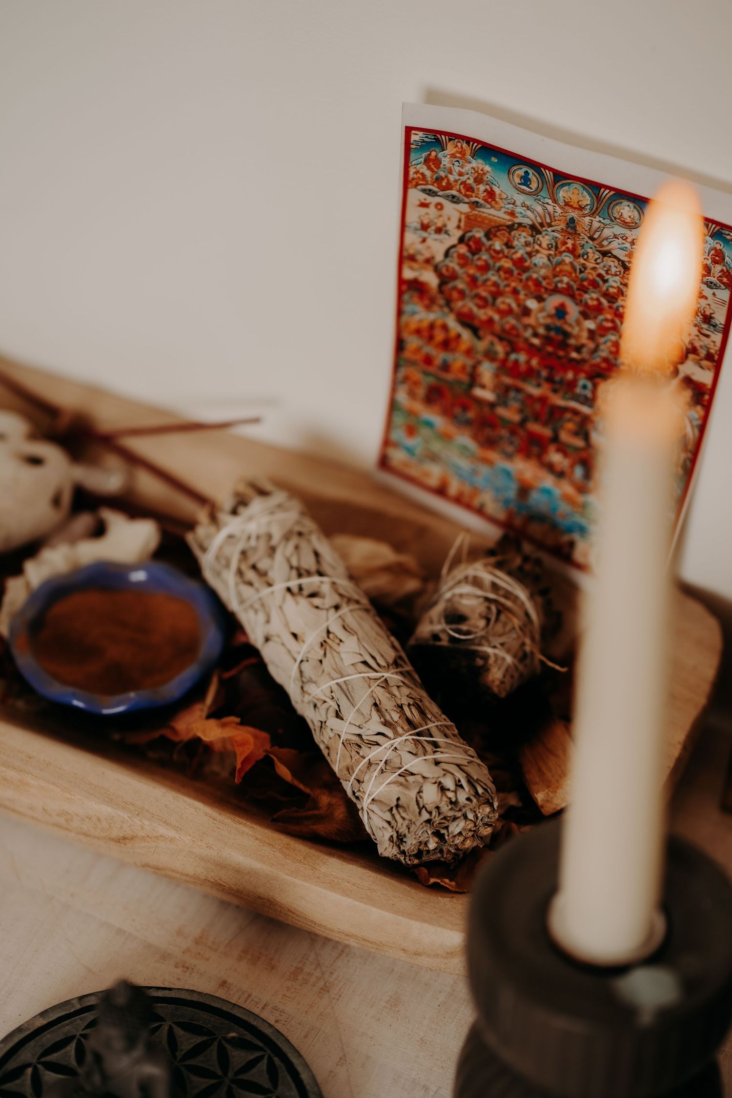 Decorative table setting with white candles and sage bundles in warm lighting.