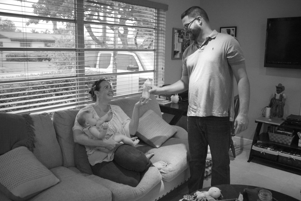 Black and white candid shot of family relaxing together on living room couch.