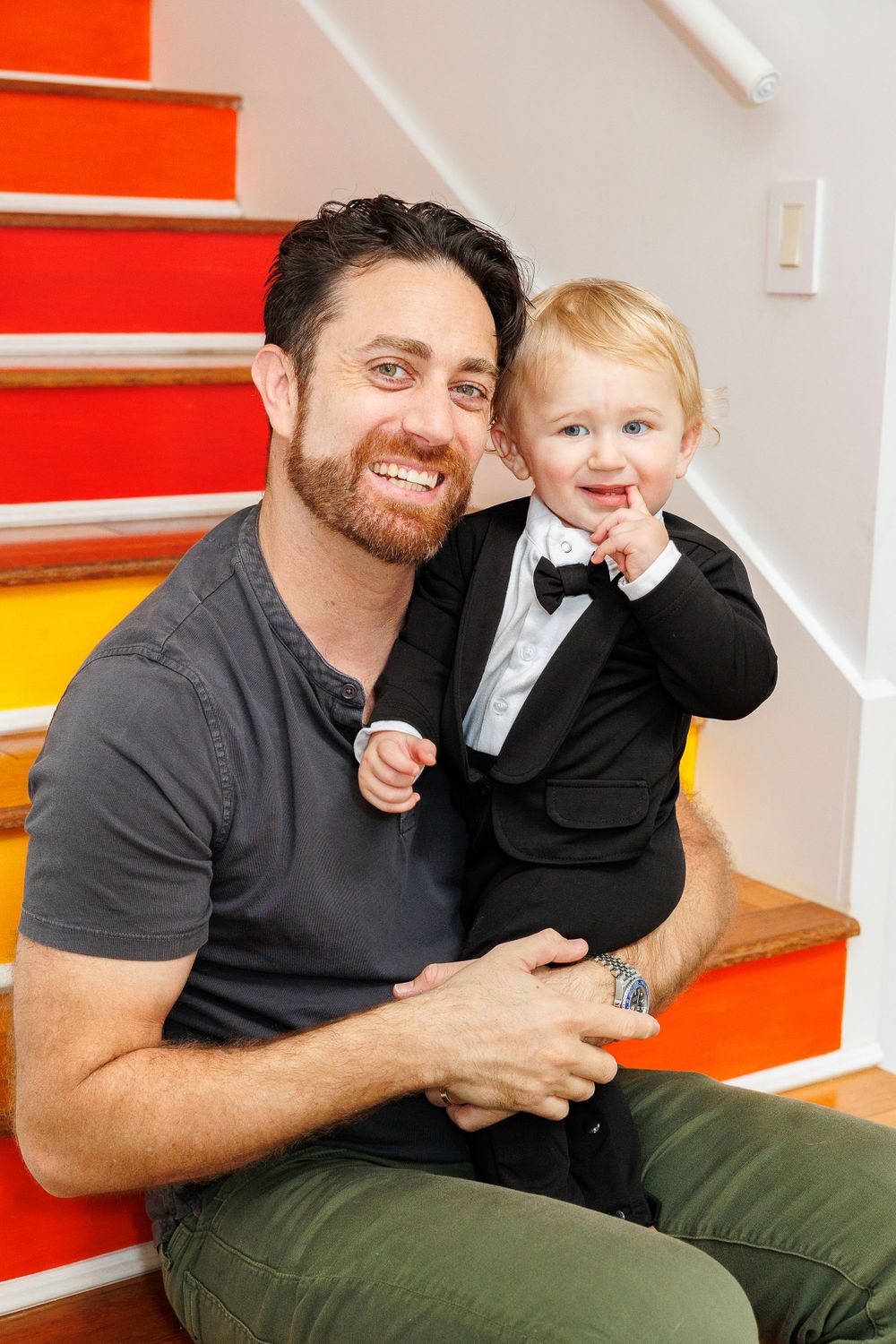 Sweet family moment on colorful rainbow stairs with toddler in formal wear.