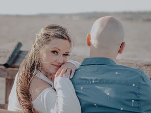 Romantic beach engagement photo of couple in casual attire.
