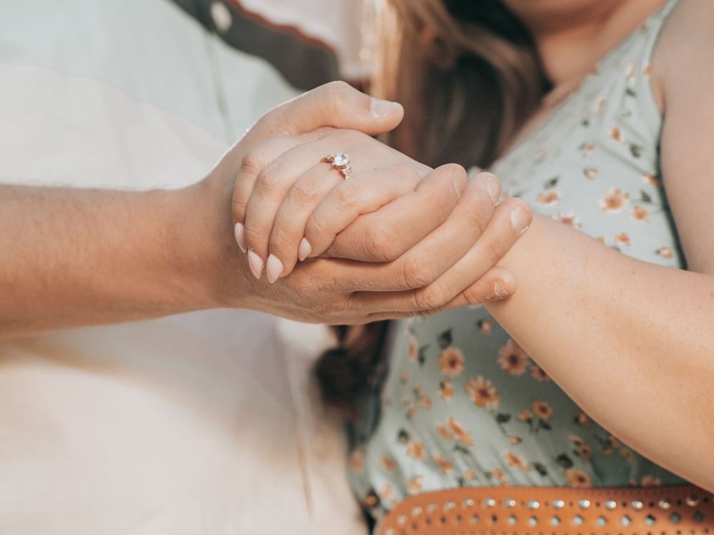 Close up of couple's hands with engagement ring in soft natural lighting.