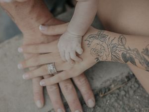 Close up of hands with tattoos and rings stacked together showing wedding bands.