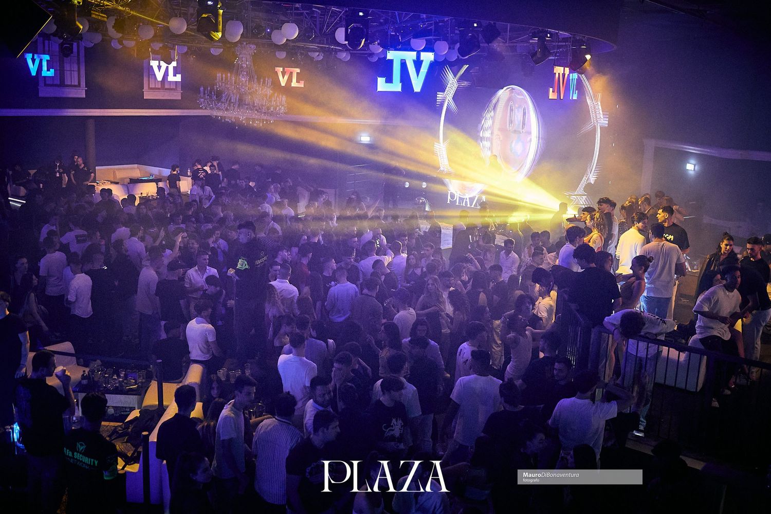 Crowded nightclub with neon lights and illuminated VIP signs creating an energetic atmosphere.