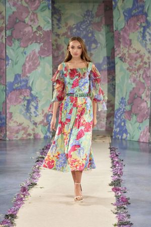 Floral print midi dress with puff sleeves on runway with watercolor backdrop and scattered petals.