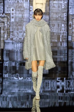 Cozy gray sweater dress with matching knee-high boots against industrial backdrop.