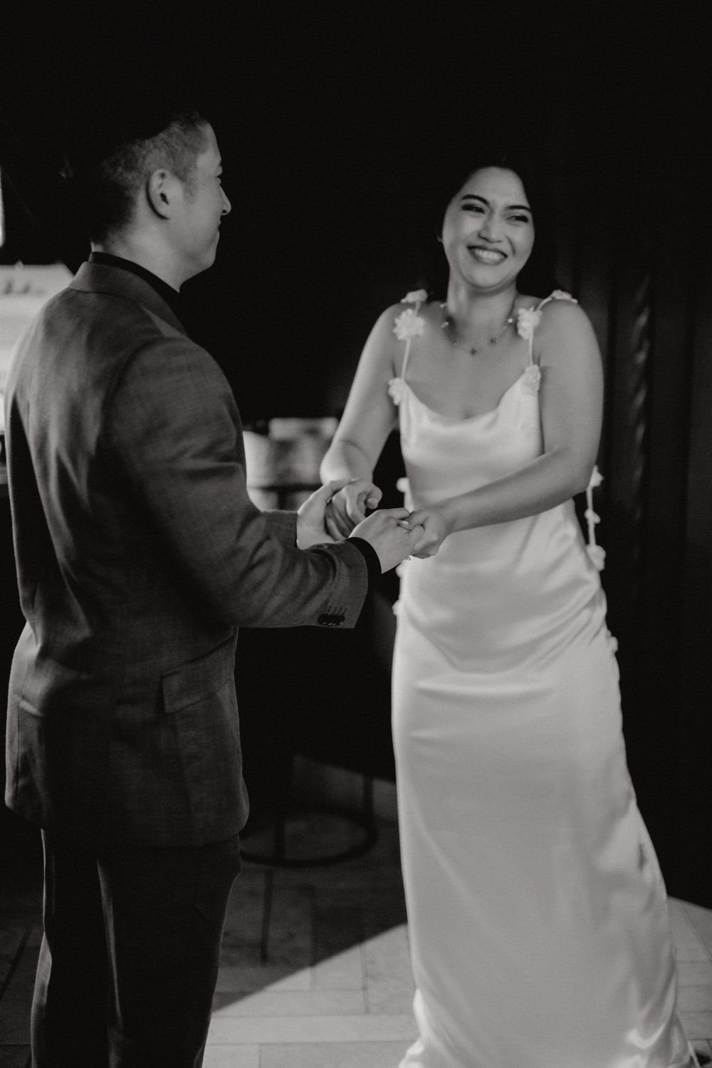 Black and white candid photo of newlyweds sharing a lighthearted moment during their first dance.