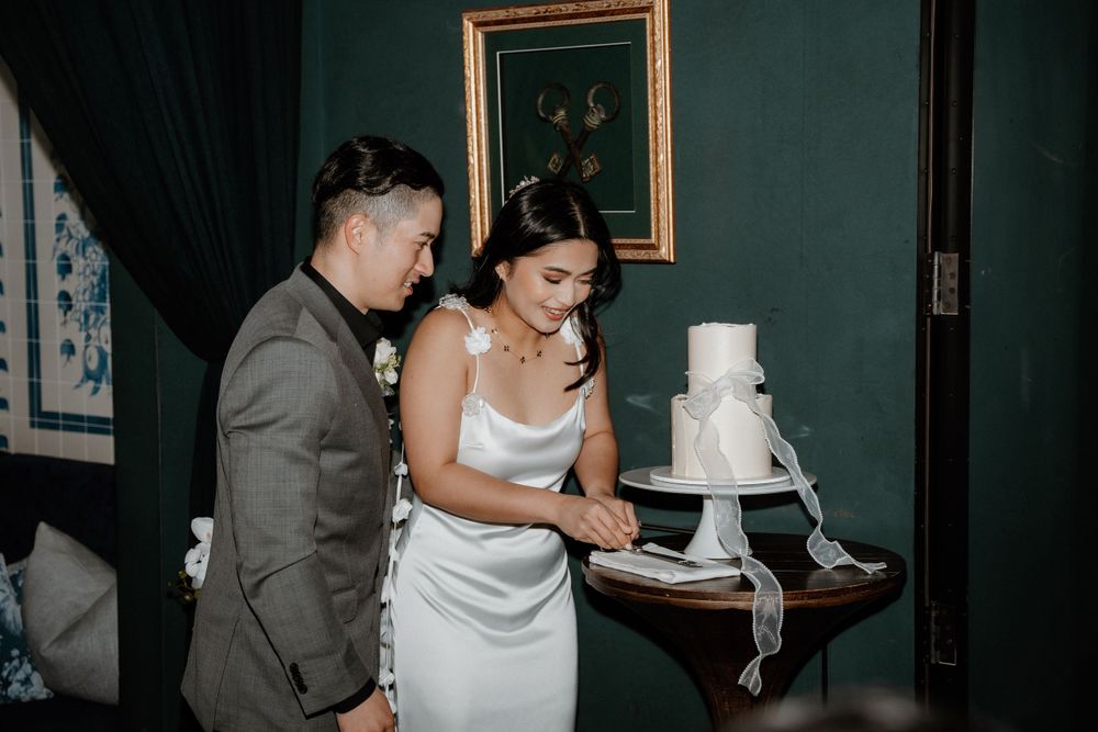 A couple in formal attire prepares to cut their white tiered wedding cake.