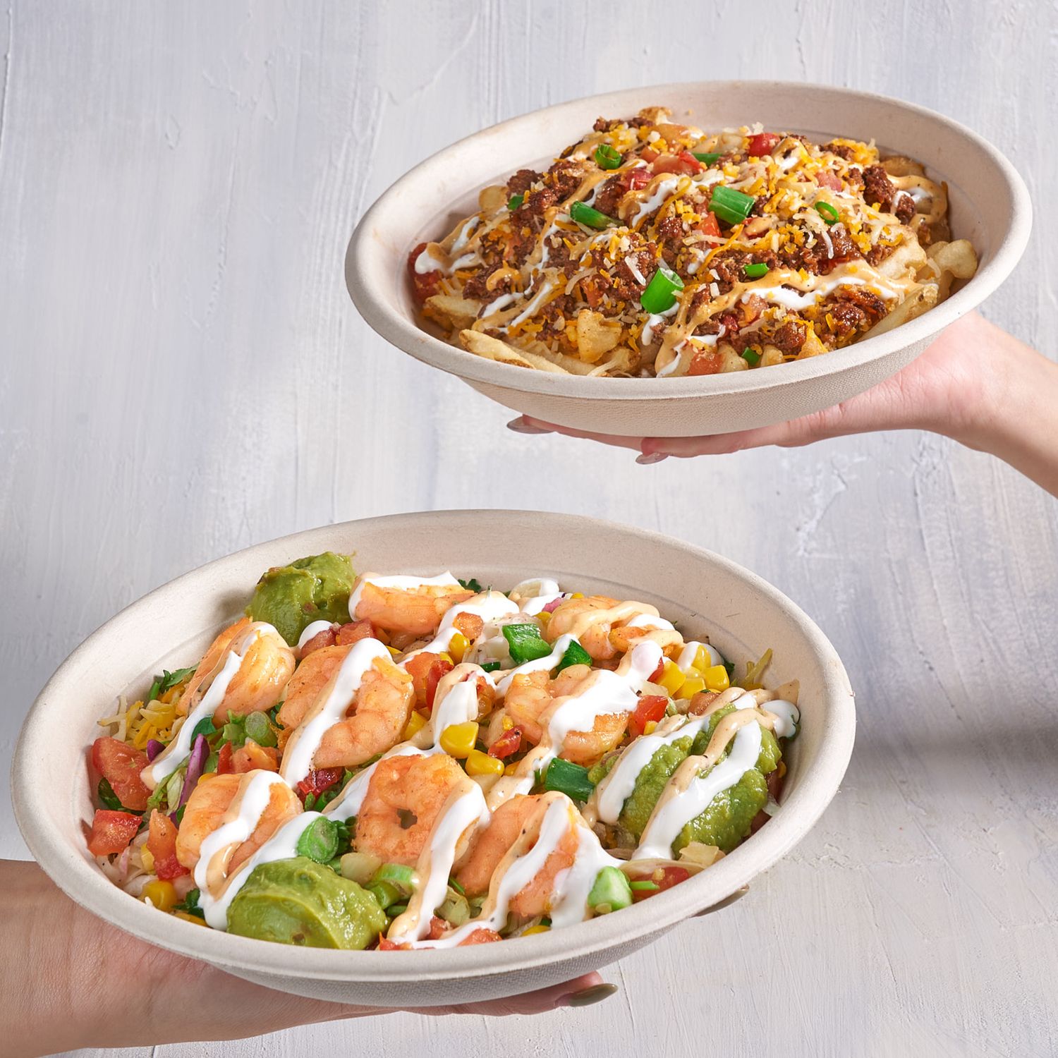 Fresh blackened shrimp bowl with crisp lettuce, avocado, and drizzled with creamy white sauce on a ceramic plate.