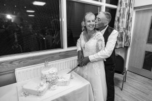Newlyweds pose beside their wedding cake in reception venue.