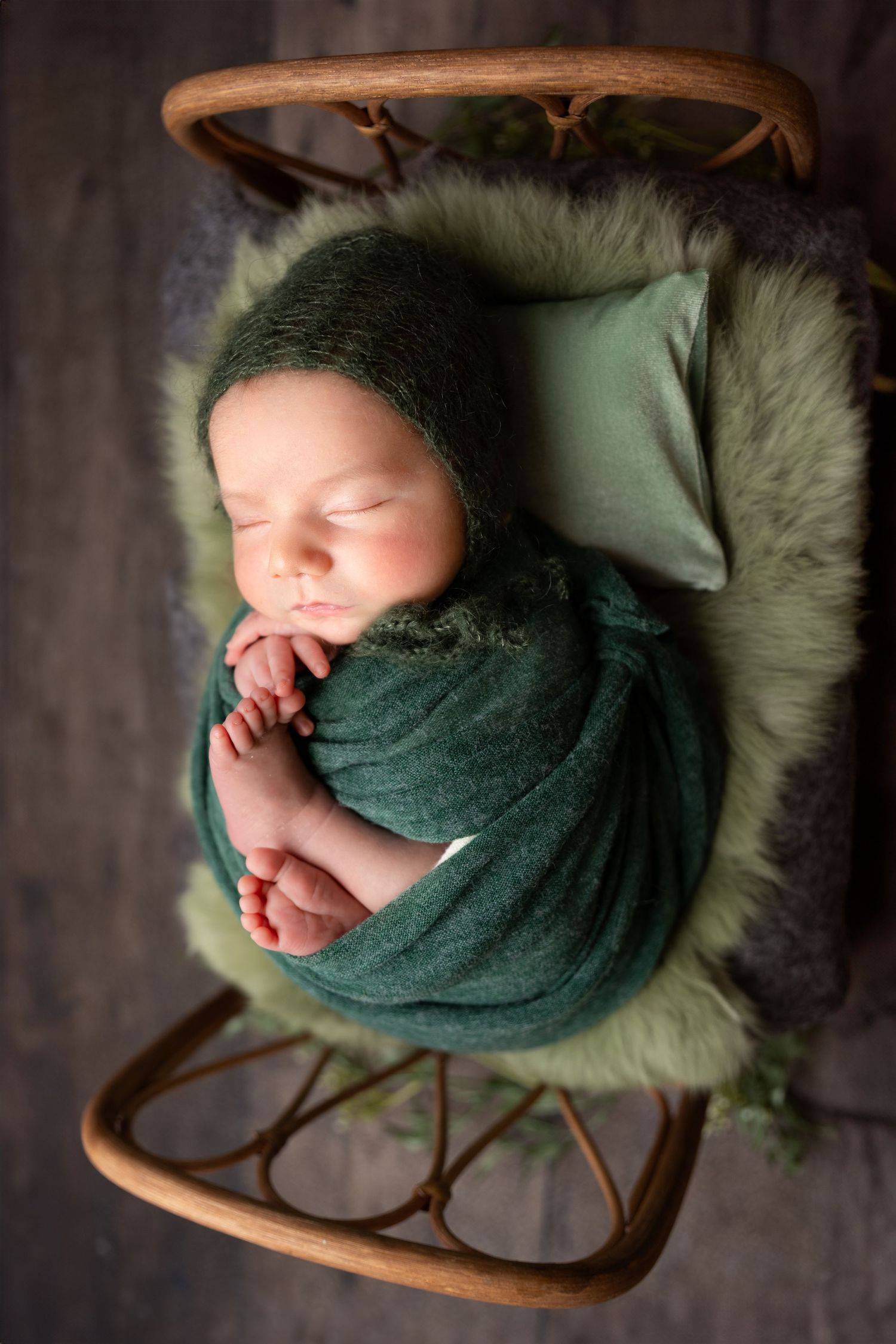 newborn photography session Sammamish WAin teal swaddle blanket sleeping peacefully in wooden bowl with white fur lining.