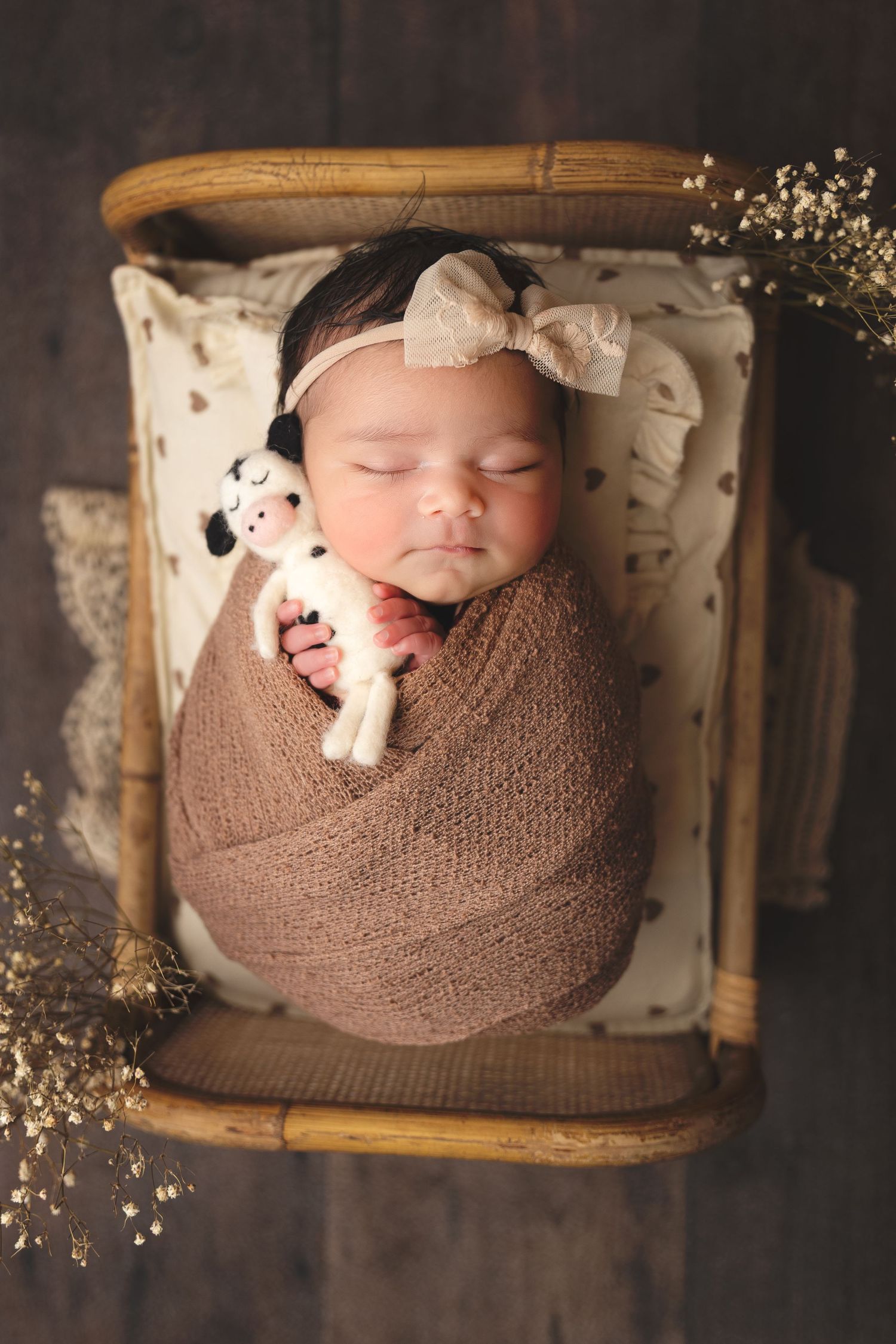 newborn photography session Sammamish WA wrapped in a brown knit blanket with small stuffed animals and floral accents in a wooden basket.
