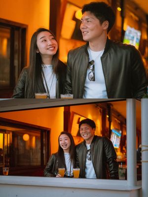 Couple laughing together with drinks at a warmly lit outdoor bar with orange ambient lighting.