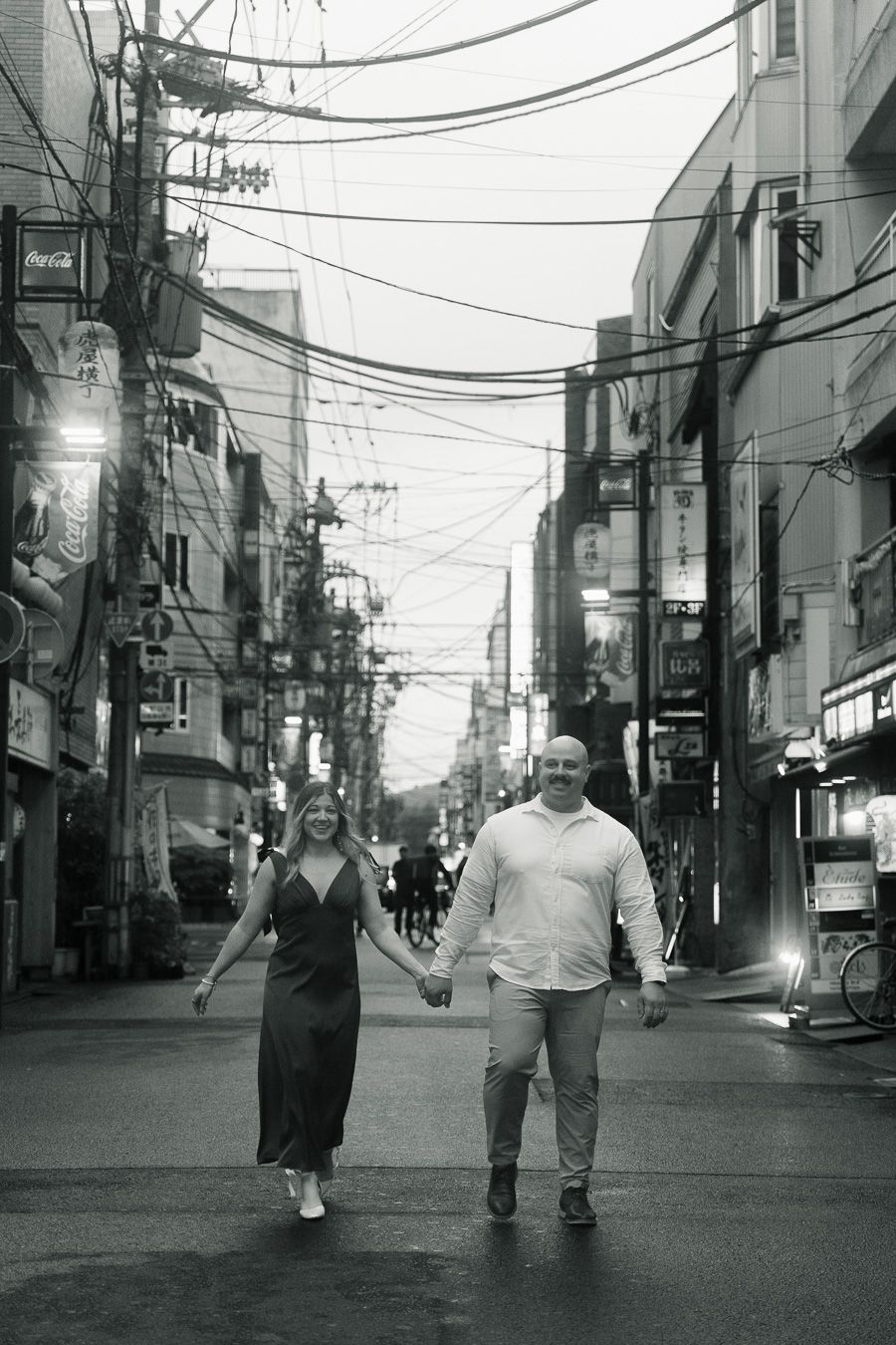 Couple holding hands walking down a bustling urban street in black and white photo.