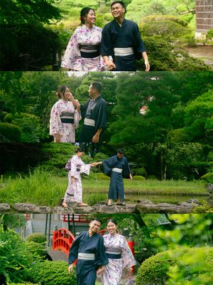 Couple in traditional Japanese kimono and yukata posing in a lush green Japanese garden with a red bridge.