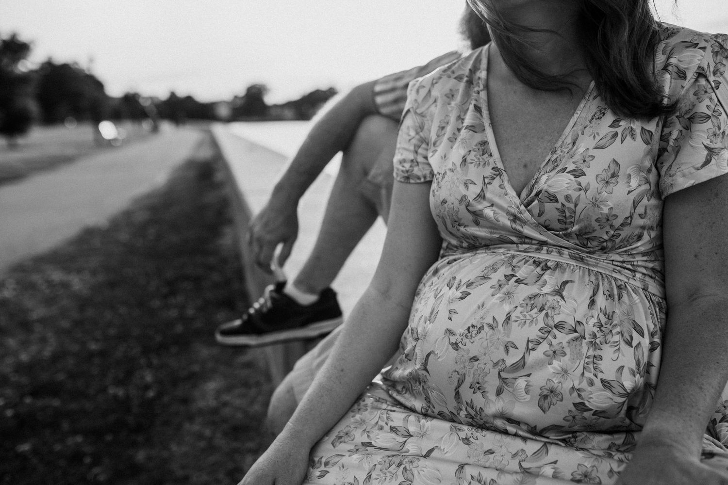 pregnant woman sitting on the seawall with her husband in portsmouth, virginia