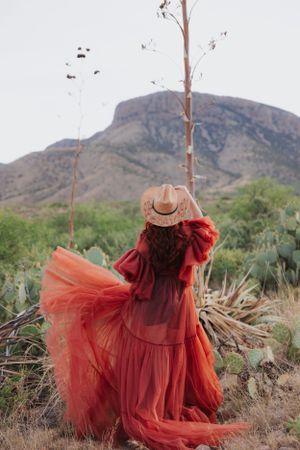 Dreamy red tulle gown contrasts with rugged desert landscape and mountain views.