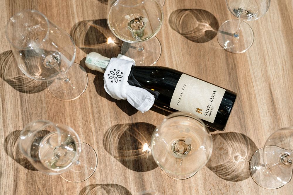An open wine bottle lying on a wooden table surrounded by empty wine glasses viewed from above.