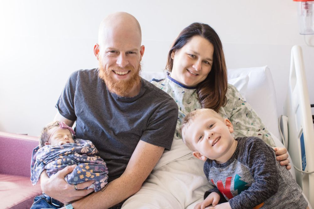 Happy family moment in hospital room with newborn baby.